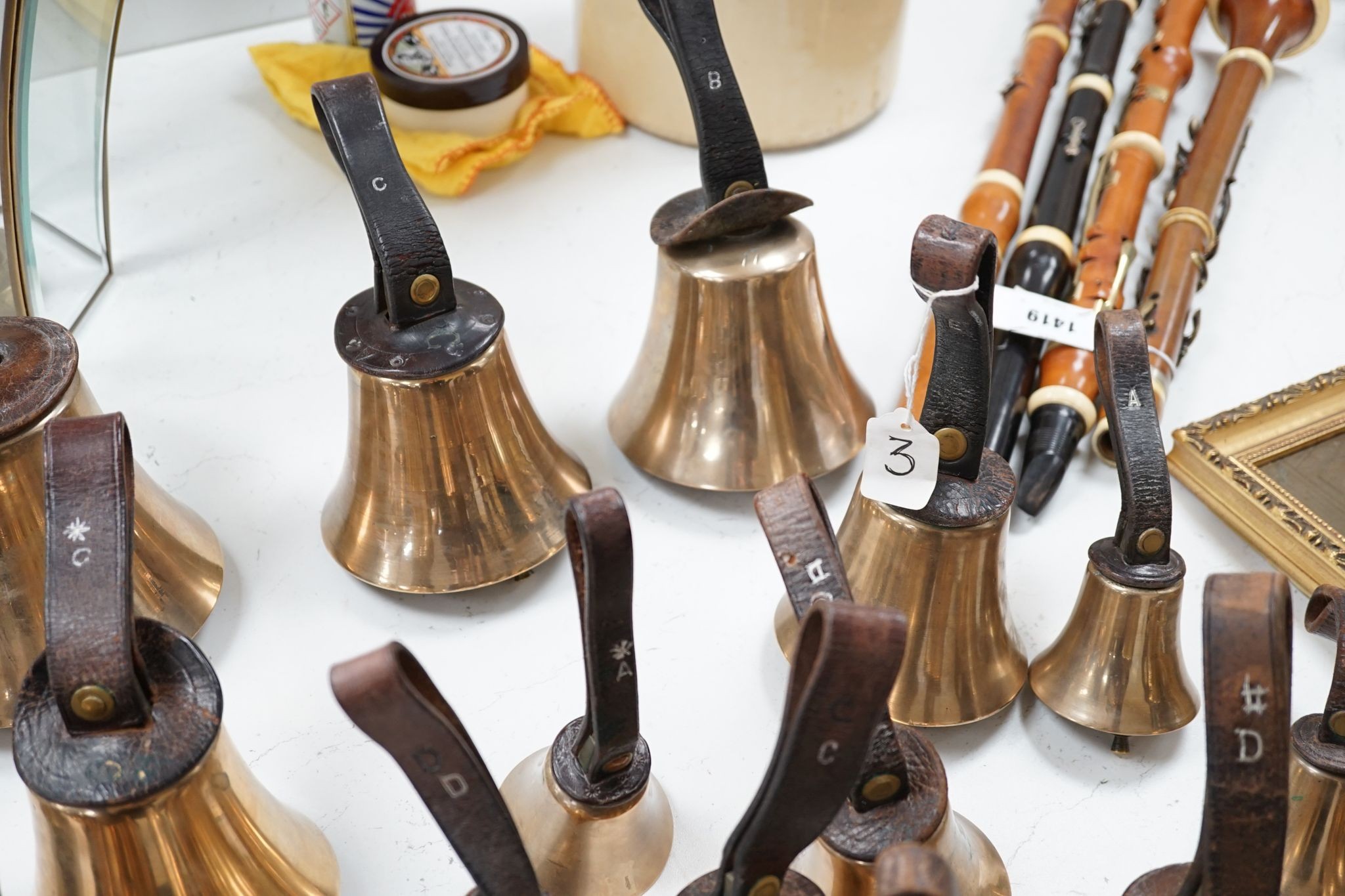 A rare set of 32 Whitechapel musical handbells, full chromatic scale, circa 1900, largest 23cm, including leather strap.